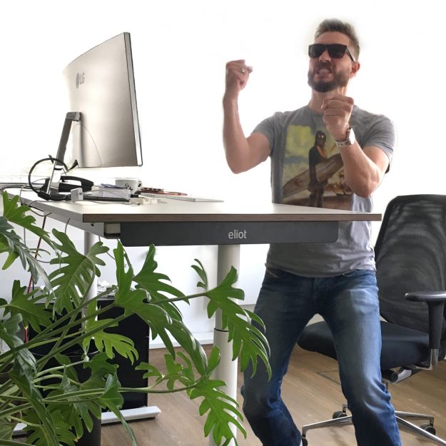 Jubelnder Mann vor eliot Schreibtisch.