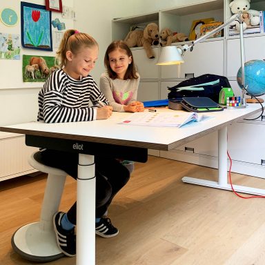 Kinder in Kinderzimmer mit höhenverstellbarem Schreibtisch.