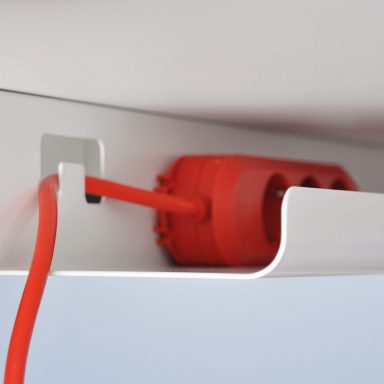 Weiße Kabelwanne mit roter Steckdosenleiste.