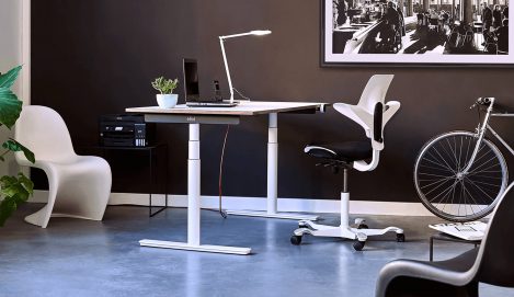 Ein Büro mit moderner Einrichtung und einem weißen höhenverstellbaren Schreibtisch.