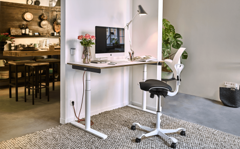 Computer auf einem weißen höhenverstellbaren Schreibtisch mit rotem Kabel.