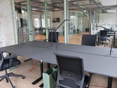 Offene Büros mit höhenverstellbaren Schreibtischen und Stühlen und Lampen.