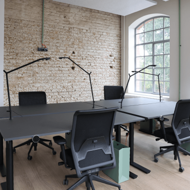 Offene Büros mit höhenverstellbaren Schreibtischen und Stühlen und Lampen.