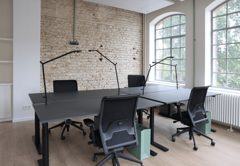 Offene Büros mit höhenverstellbaren Schreibtischen und Stühlen und Lampen.