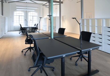 Offene Büros mit höhenverstellbaren Schreibtischen und Stühlen und Lampen.