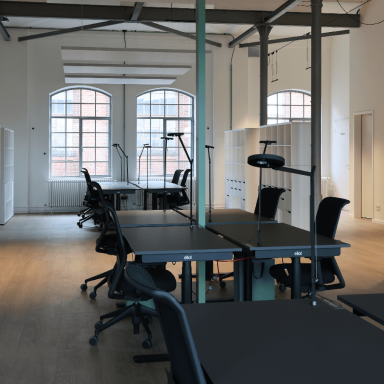 Offene Büros mit höhenverstellbaren Schreibtischen und Stühlen und Lampen.