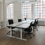 Offene Büros mit höhenverstellbaren Schreibtischen und Stühlen und Lampen.