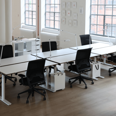 Offene Büros mit höhenverstellbaren Schreibtischen und Stühlen und Lampen.