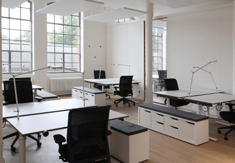 Offene Büros mit höhenverstellbaren Schreibtischen und Stühlen und Lampen.