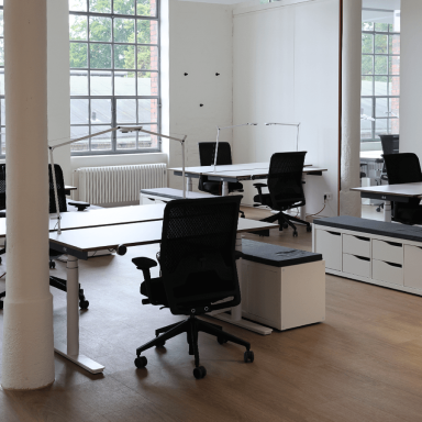 Offene Büros mit höhenverstellbaren Schreibtischen und Stühlen und Lampen.