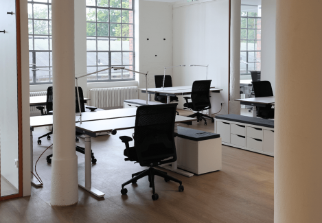 Offene Büros mit höhenverstellbaren Schreibtischen und Stühlen und Lampen.