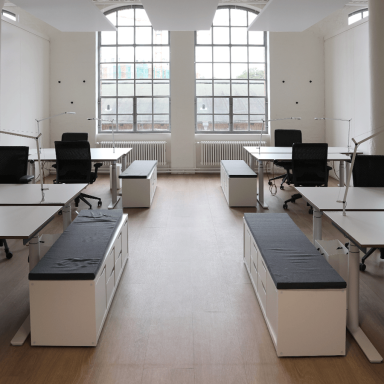 Offene Büros mit höhenverstellbaren Schreibtischen und Stühlen und Lampen.