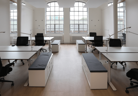 Offene Büros mit höhenverstellbaren Schreibtischen und Stühlen und Lampen.