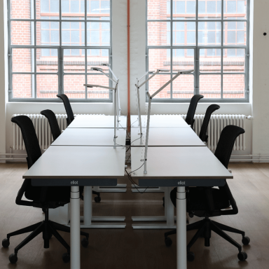 Ein Konferenzraum mit höhenverstellbaren Schreibtischen und Stühlen und Lampen.