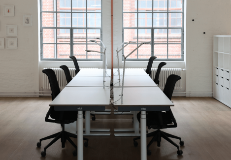 Ein Konferenzraum mit höhenverstellbaren Schreibtischen und Stühlen und Lampen.