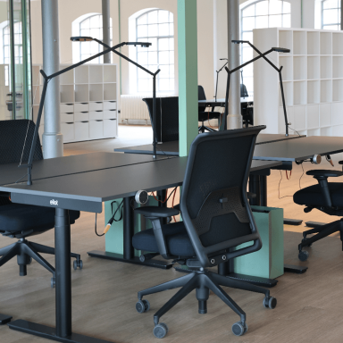 Ein Konferenzraum mit höhenverstellbaren Schreibtischen und Stühlen und Lampen.